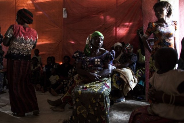 A displaced Congolese woman sits inside a church, whish serves as a shelter by night, on December 15, 2017 in Beni. Attacks allegedly carried out by the Ugandan Muslim Group, ADF in Eastern Democratic Republic of the Congo (DRC), have displaced thousands people since October 2017.  / AFP PHOTO / JOHN WESSELS