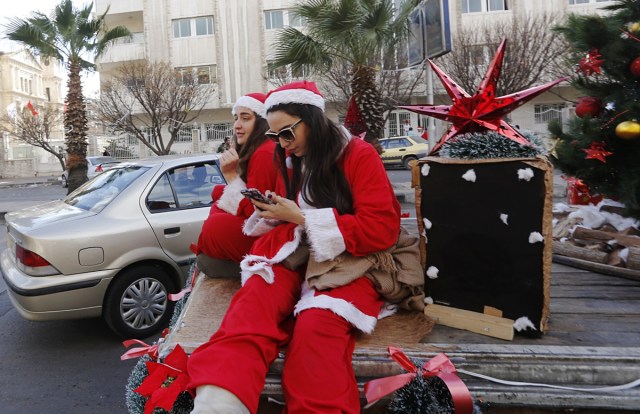 Syrians dressed in Santa Claus outfits roam the streets of the capital Damascus on the back of a decorated vehicle on December 24, 2017 for Christmas eve celebrations. / AFP PHOTO / Louai Beshara