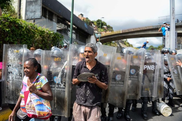 People shout slogans during a protest against the shortage of food, amid Fuerzas Armadas avenue in Caracas on December 28, 2017. As Venezuelans protest in Caracas demanding the government's prommised pork -the main dish of the Christmas and New Year's dinner-, President Nicolas Maduro attributes the shortage to international sabotage. / AFP PHOTO / FEDERICO PARRA