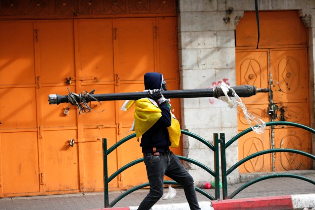 HEB18. HEBRÓN (PALESTINA), 20/12/2017.- Palestinos carga con una farola durante disturbios con las tropas israelíes por la decisión del presidente estadounidense, Donald Trump, de reconocer Jerusalén como capital israelí, en Hebrón (Palestina) hoy, 20 de diciembre de 2017. EFE/ Abed Al Hashlamoun