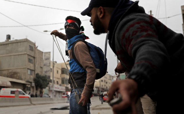 Palestinian protestors throw stones towards Israeli forces during clashes near the Qalandia checkpoint in the Israeli occupied West Bank on December 20, 2017 as protests continue following the US president's controversial recognition of Jerusalem as Israel's capital. / AFP PHOTO / THOMAS COEX