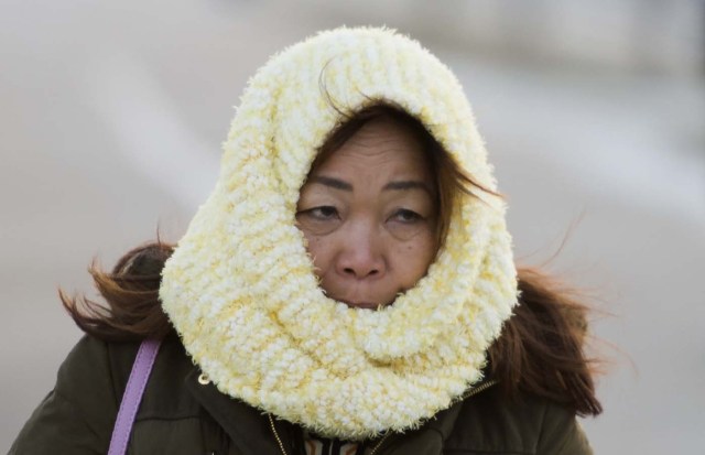 A woman covers her face as she tries to stay warm while walking on the National Mall in Washington, DC on January 5, 2018. The National Weather Service said that very cold temperatures and wind chills will follow for much of the eastern third of the US through the weekend. A cold wave gripping a large section of the United States had already been blamed for a dozen deaths. / AFP PHOTO / ANDREW CABALLERO-REYNOLDS