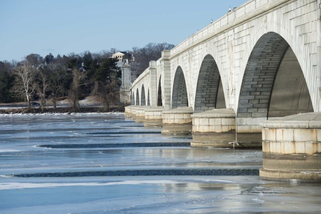 Parts of the Arlington cemetary is seen across a frozen Potomac river in Washington, DC on January 5, 2018. The National Weather Service said that very cold temperatures and wind chills will follow for much of the eastern third of the US through the weekend. A cold wave gripping a large section of the United States had already been blamed for a dozen deaths. / AFP PHOTO / ANDREW CABALLERO-REYNOLDS