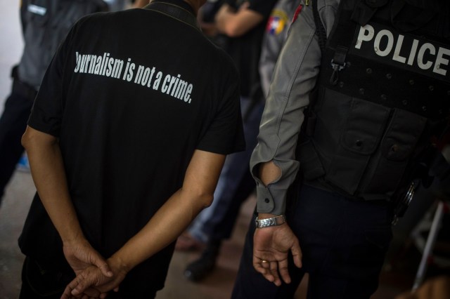 A local journalist (L) stands next to a police officer as Reuters journalists Kyaw Soe Oo and Wa Lone appear in court in Yangon on January 10, 2018. Myanmar police formally filed charges on January 10 against two Reuters reporters accused of breaching the Official Secrets Act, a judge said, an offence that carries up to 14 years in prison. / AFP PHOTO / YE AUNG THU