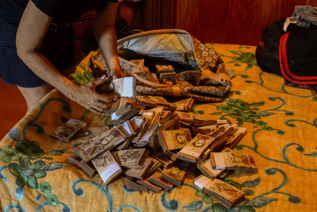 A woman counts the monthly pay of her employees in the village of Chichiriviche de la Costa, some 70 km northwest of Caracas on January 13, 2018. The inhabitants of the village of Chichiriviche de la Costa, which depends on tourism, have come up with an ingenious way to deal with the lack of cash and internet connection. / AFP PHOTO / FEDERICO PARRA