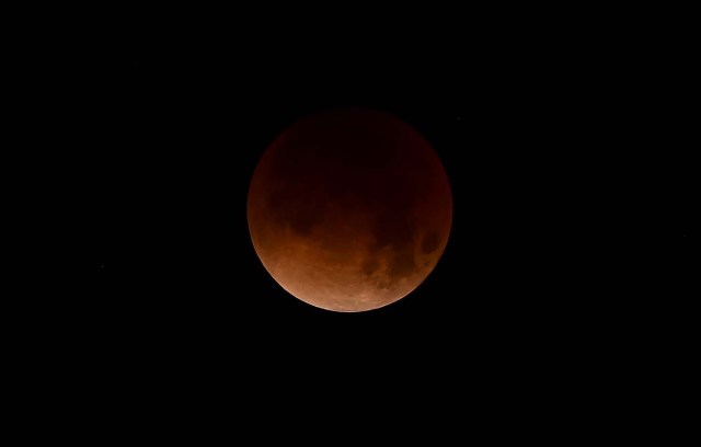 A Super Blue Blood Moon hovers over Los Angeles, California in the early hours of January 31, 2018, during an event not seen since 1866 when three fairly common lunar happenings occur at the same time. Stargazers across large swathes of the globe -- from the streets of Los Angeles to the slopes of a smouldering Philippine volcano -- had the chance to witness a rare "super blue blood Moon" Wednesday, when Earth's shadow bathed our satellite in a coppery hue.The celestial show is the result of the Sun, Earth, and Moon lining up perfectly for a lunar eclipse just as the Moon is near its closest orbit point to Earth, making it appear "super" large. / AFP PHOTO / Frederic J. Brown