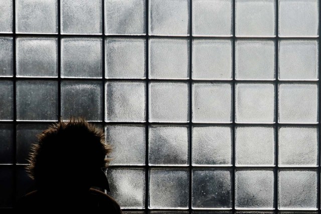 A woman stands bumbled up from the cold outside a bus terminal in Queens, New York, U.S. January 2, 2018. REUTERS/Shannon Stapleton