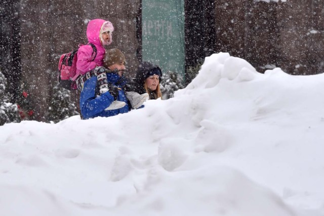 People walk through a snowdrift during heavy snowfall in the centre of Kiev on March 1, 2018. Fresh heavy snowfalls and icy blizzards were expected to lash Europe on March 1, 2018 as the region shivers in a deadly deep-freeze that has gripped countries from the far north to the Mediterranean south. / AFP PHOTO / Sergei SUPINSKY