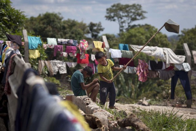 Venezuelan indigenous children play inside a temporary shelter in the city of Pacaraima, Roraima, Brazil, on February 28, 2018. Hundreds of Venezuelan indigenous people, most of them Warao indigenous, from the northeast of the country, escaped from turmoil and hunger to Brazil during last years. In improvised shelters the situation has improved for some of them, but the migration increasing influx and the lack of plans generates uncertainty. / AFP PHOTO / Mauro Pimentel / TO GO WITH AFP STORY by Paula RAMÓN