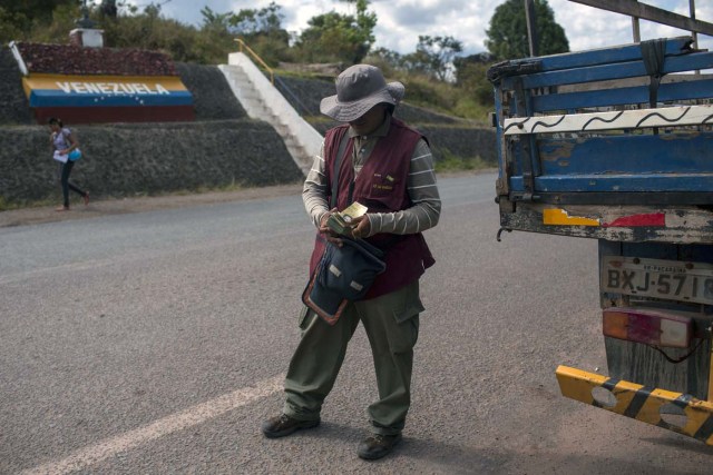 Man sells Venezuelan and Brazilian money at the border between Brazil and Venezuela at Pacaraima, Roraima, Brazil, on February 27, 2018. According to local authorities, around one thousand refugees are crossing the Brazilian border each day from Venezuela. With the constant influx of Venezuelan immigrants, most are living in shelters and the streets of Boa Vista and Pacaraima cities, looking for work, medical care and food. Most are legalizing their status to stay and live in Brazil. / AFP PHOTO / Mauro Pimentel / TO GO WITH AFP STORY by Paula RAMÓN