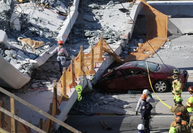 personal de rescate de bomberos de Miami-Dade y otras unidades de rescate trabajan en la escena donde un puente peatonal se derrumbó pocos días después de que se construyó sobre la calle 8 del suroeste permitiendo a la gente evitar la calle concurrida para llegar a Florida International University el 15 de marzo de 2018 en Miami, Florida. Los informes indican que hay un número desconocido de muertes como resultado del colapso, que aplastó al menos cinco automóviles. Joe Raedle / Getty Images / AFP