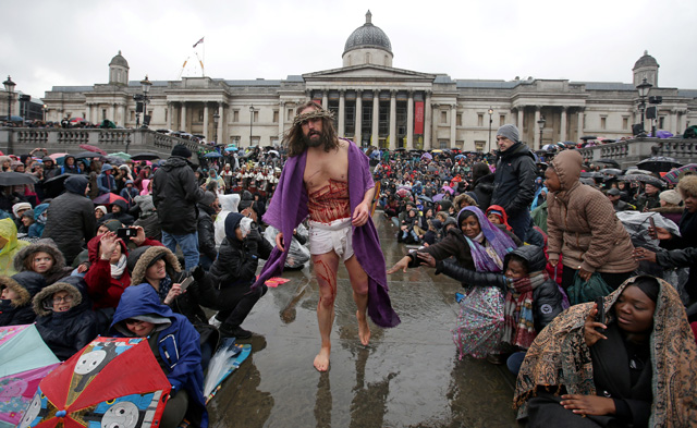 Actor James Burke-Dunsmore (C) plays the role of Jesus Christ, during a performance of Wintershall's 'The Passion of Jesus' on Good Friday in Trafalgar Square in London on March 30, 2018.  The Passion of Jesus tells the story from the Bible of Jesus's visit to Jerusalem and his crucifixion. On Good Friday 20,000 people gather to watch the Easter story in central London. One hundred Wintershall players bring their portrayal of the final days of Jesus to this iconic location in the capital. / AFP PHOTO / Daniel LEAL-OLIVAS