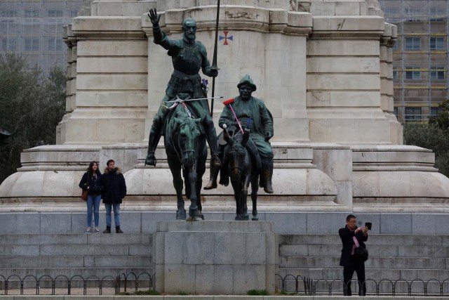 People stand near the the statue of Don Quixote and Sancho Panza decorated with house cleaning supplies during a nationwide feminist strike on International Women's Day in Madrid, Spain, March 8, 2018. REUTERS/Susana Vera