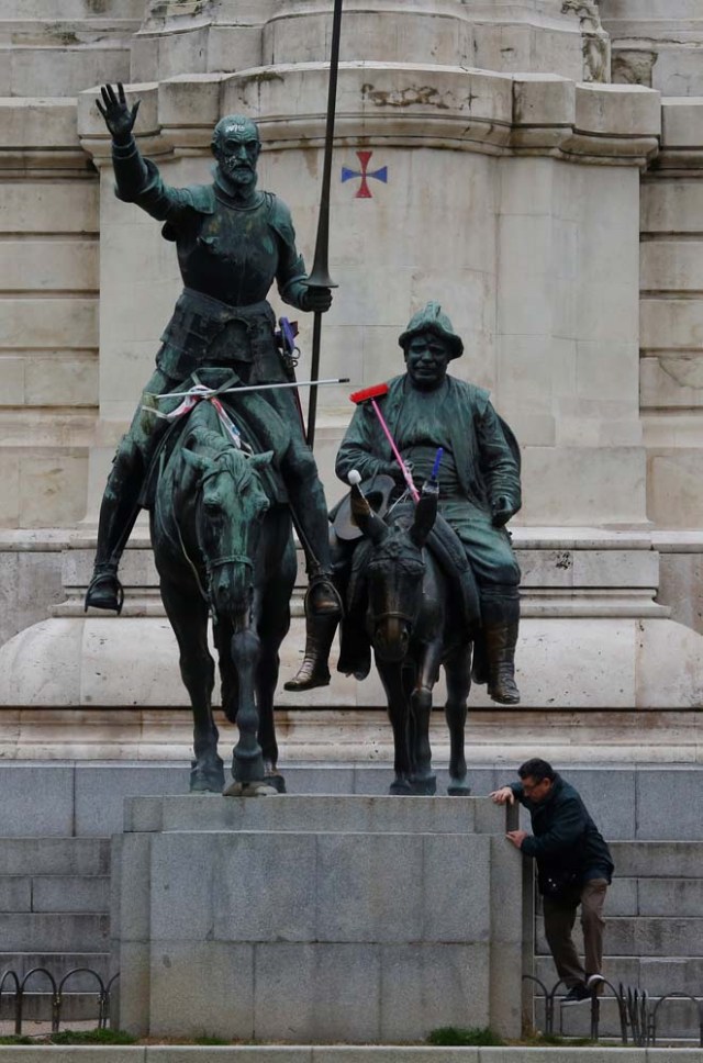 A man stands near the the statue of Don Quixote and Sancho Panza decorated with house cleaning supplies during a nationwide feminist strike on International Women's Day in Madrid, Spain, March 8, 2018. REUTERS/Susana Vera