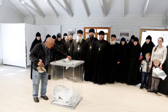 Los clérigos y monjas rusos posan para una foto grupal mientras un ciudadano ruso presenta su voto para las elecciones presidenciales de Rusia en una mesa electoral en Jerusalén, el 18 de marzo de 2018. REUTERS / Ronen Zvulun