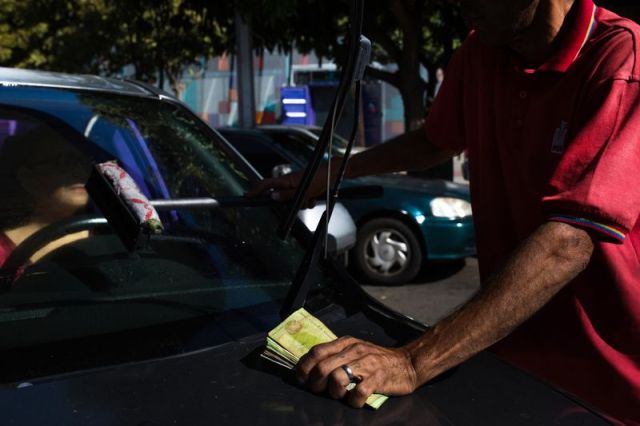 Un asistente de PDVSA tiene una pila de billetes de Bolívar mientras ayuda a un cliente en una estación de servicio en Caracas. Fotógrafo: Wil Riera / Bloomberg