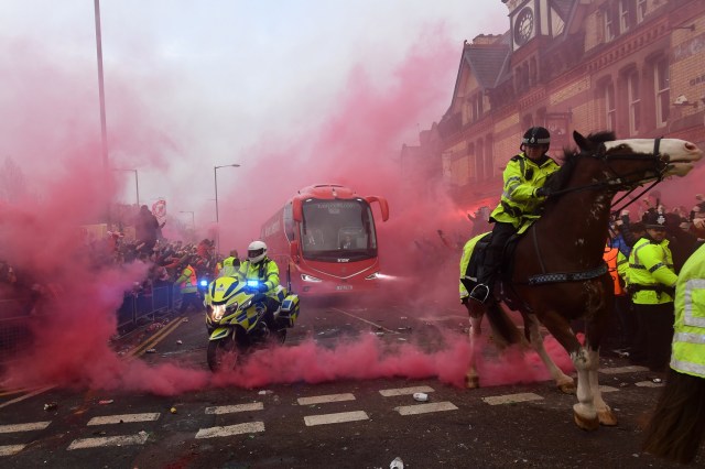 Police keep control as Liverpool players arrive by bus through smoke and beercans before the UEFA Champions League first leg quarter-final football match between Liverpool and Manchester City, at Anfield stadium in Liverpool, north west England on April 4, 2018. / AFP PHOTO / Paul ELLIS