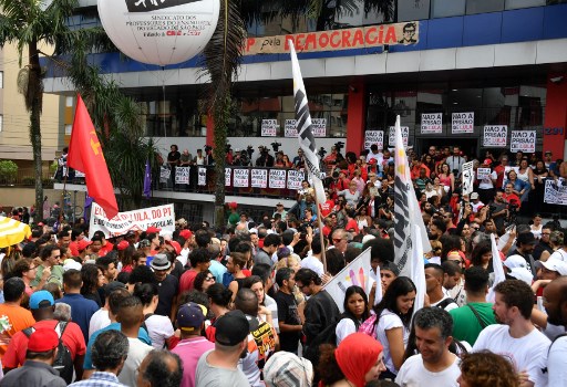 Supporters of former Brazilian president (2003-2011) Luiz Inacio Lula da Silva wait outside the metalworkers' union building in Sao Bernardo do Campo, in metropolitan Sao Paulo, Brazil, on April 7, 2018. The imminent jailing of Brazil's Lula may have dealt a crippling blow to the country's left, but it has also shaken up their political rivals on the right, most of whom are also under investigation for graft. There has been a deafening silence around the arrest of Luiz Inacio Lula da Silva, who is facing 12 years behind bars for taking bribes and money laundering, especially given that his political demise likely removes the main frontrunner in October's presidential elections. / AFP PHOTO / Nelson Almeida