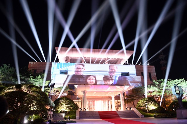  A picture of North Korea's leader Kim Jong Un and South Korea's President Moon Jae-in from earlier in the day is beamed onto the Peace House where the talks had taken place, during a closing ceremony at the end of their historic summit at the truce village of Panmunjom on April 27, 2018. The leaders of the two Koreas held a landmark summit on April 27 after a highly symbolic handshake over the Military Demarcation Line that divides their countries, with the North's Kim Jong Un declaring they were at the "threshold of a new history". / AFP PHOTO / Korea Summit Press Pool / - 581/5000 Una foto del líder norcoreano Kim Jong Un y del presidente surcoreano Moon Jae-in emitida en la Casa de la Paz donde se habían celebrado las conversaciones, durante una ceremonia de clausura al final de su histórica cumbre en la aldea de la tregua de Panmunjom el 27 de abril de 2018. Los líderes de las dos Coreas celebraron una cumbre histórica el 27 de abril después de un apretón de manos muy simbólico sobre la Línea de Demarcación Militar que divide sus países, con Kim Jong Un del Norte declarando que estaban en el "umbral de una nueva historia". / AFP PHOTO / Korea Summit Press Pool / -