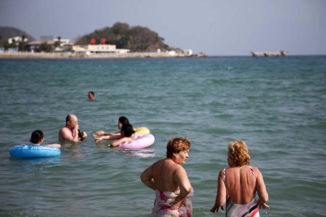 epa02802520 Vacationers relax on Dadonghai beach on Sanya island, Hainan province, China, on 30 June 2011. Due to its year round warm climate and relatively cheap prices, Sanya has becoming a vacation hot spot for Russians, by far the most numerous foreign visitors that make their vacation on the tropical island. EPA/QILAI SHEN