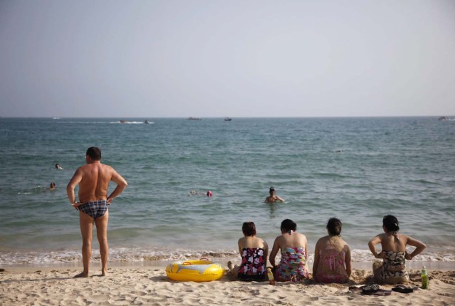 epa02802527 Vacationers relax on Dadonghai beach on Sanya, Hainan province, China, on 30 June 2011. Due to its year round warm climate and relatively cheap prices, Sanya has becoming a vacation hot spot for Russians, by far the most numerous foreign visitors that make their vacation on the tropical island. EPA/QILAI SHEN