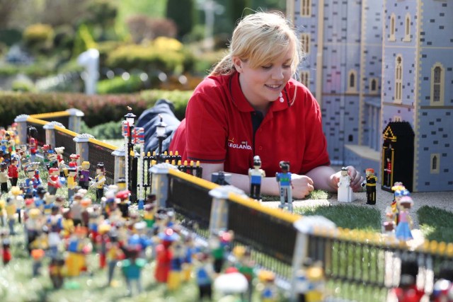 Legoland employee, Lucy, poses putting a Lego model of US actress Meghan Markle (L) in place next to her husband-to-be Britain's Prince Harry (R) outside a Lego-brick model of Windsor Castle at Legoland in Windsor on May 8, 2018 during a photo call for its attraction celebrating the upcoming royal wedding. Prince Harry and US actress Meghan Markle will marry on May 19 at St. George's Chapel at Windsor Castle. / AFP PHOTO / Daniel LEAL-OLIVAS