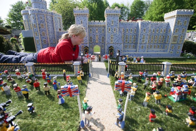 Legoland employee, Lucy, poses putting a Lego model of US actress Meghan Markle (L) in place next to her husband-to-be Britain's Prince Harry (R) outside a Lego-brick model of Windsor Castle at Legoland in Windsor on May 8, 2018 during a photo call for its attraction celebrating the upcoming royal wedding. Prince Harry and US actress Meghan Markle will marry on May 19 at St. George's Chapel at Windsor Castle. / AFP PHOTO / Daniel LEAL-OLIVAS