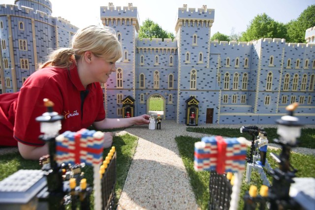 Legoland employee, Lucy, poses putting a Lego model of US actress Meghan Markle (L) in place next to her husband-to-be Britain's Prince Harry (R) outside a Lego-brick model of Windsor Castle at Legoland in Windsor on May 8, 2018 during a photo call for its attraction celebrating the upcoming royal wedding. Prince Harry and US actress Meghan Markle will marry on May 19 at St. George's Chapel at Windsor Castle. / AFP PHOTO / Daniel LEAL-OLIVAS