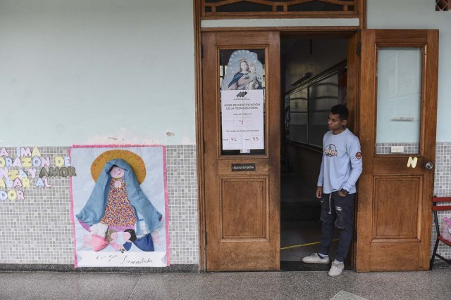 A Venezuelan electoral official waits for voters at an empty polling station during the presidential elections in Caracas on May 20, 2018 Venezuelans, reeling under a devastating economic crisis, began voting Sunday in an election boycotted by the opposition and condemned by much of the international community but expected to hand deeply unpopular President Nicolas Maduro a new mandate / AFP PHOTO / Carlos Becerra