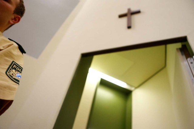 FILE PHOTO: A crucifix on the wall is pictured on a wall in the courtroom before proceedings are resumed in the trial of Beate Zschaepe and four others involving neo-Nazi racist murders, in Munich May 14, 2013. REUTERS/Kai Pfaffenbach/File Photo