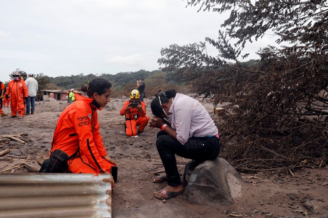 Eufemia Garcia, 48, who lost 50 members of her family during the eruption of the Fuego volcano, reacts while talking to a member of the Mexican Topos rescue team after human remains were found near the area where her house is buried at San Miguel Los Lotes in Escuintla, Guatemala June 10, 2018. REUTERS/Carlos Jasso