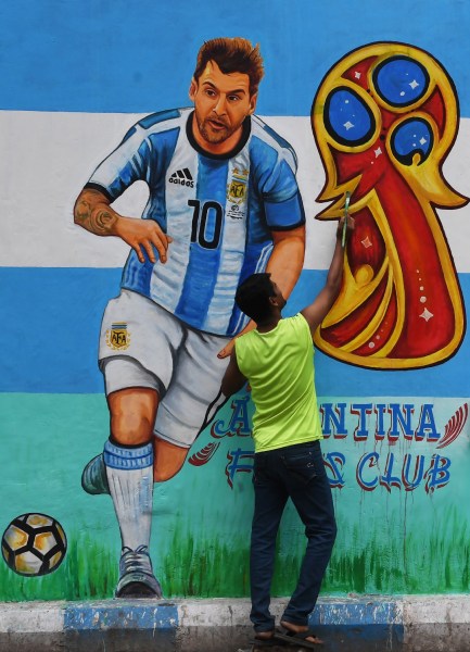 Un fanático del fútbol indio pinta una foto del futbolista argentino Lionel Messi en una carretera, antes de la próxima Copa Mundial FIFA 2018, en Calcuta el 10 de junio de 2018. Dibyangshu SARKAR / AFP