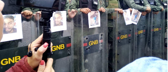 Estudiantes pegan carteles con sus compañeros caídos durante las protestas a efectivos militares. Imagen cortesía. 